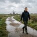 Man wandelt stevig door de polder in lichte herfstregen